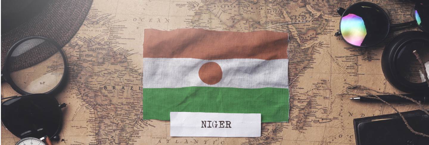 Niger flag between traveler's accessories on old vintage map. overhead shot