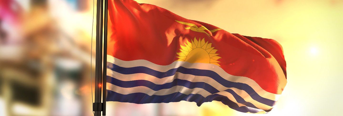 Kiribati flag against city blurred background at sunrise backlight