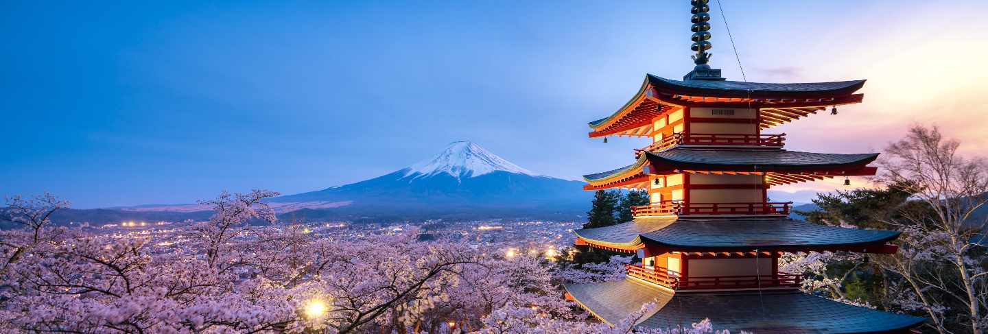 Japan at chureito pagoda and mt. fuji in the spring with cherry blossoms full bloom during twilight.