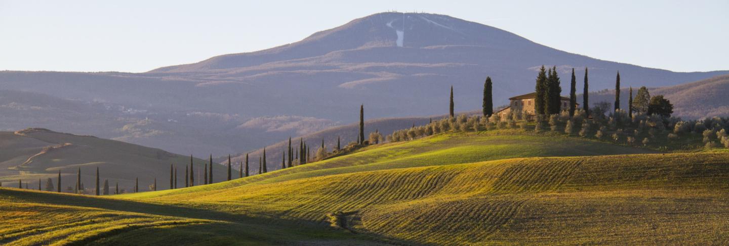 Beautiful shot of a country house in the middle of a field surrounded by hills under the clear sky