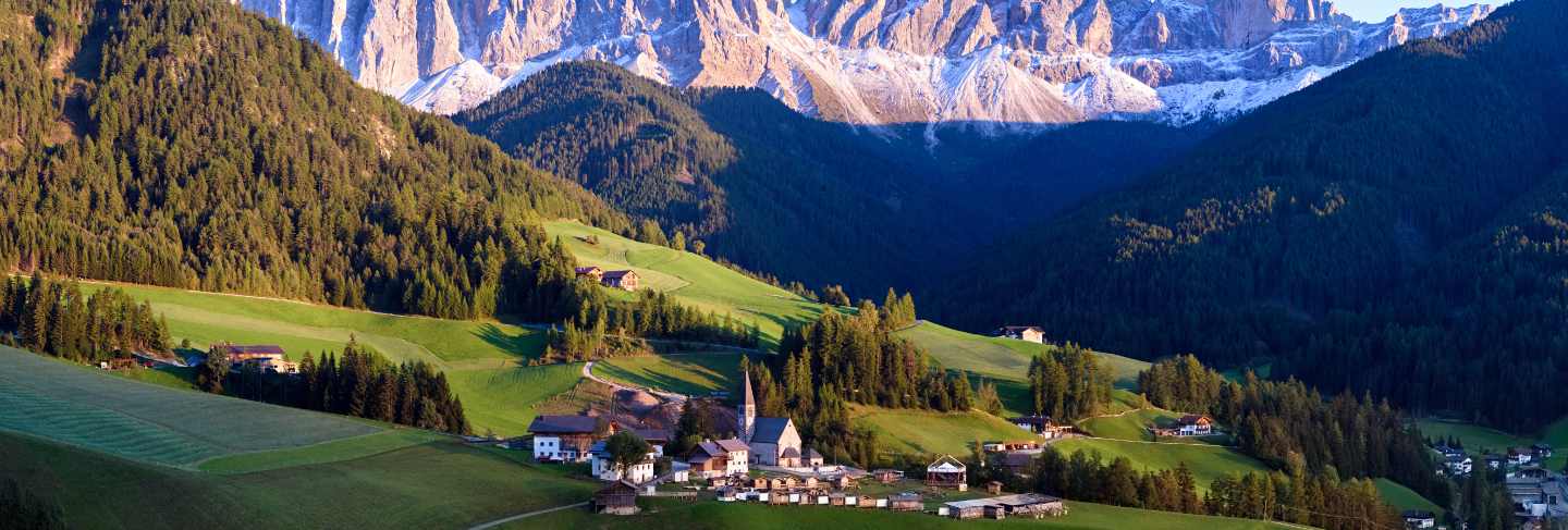 Alpine village with dolomites mountains on background