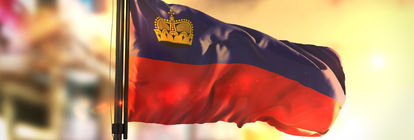 Liechtenstein flag against city blurred background at sunrise backlight