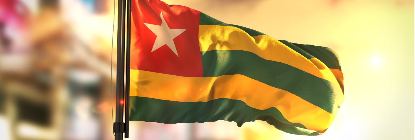 Togo flag against city blurred background at sunrise backlight