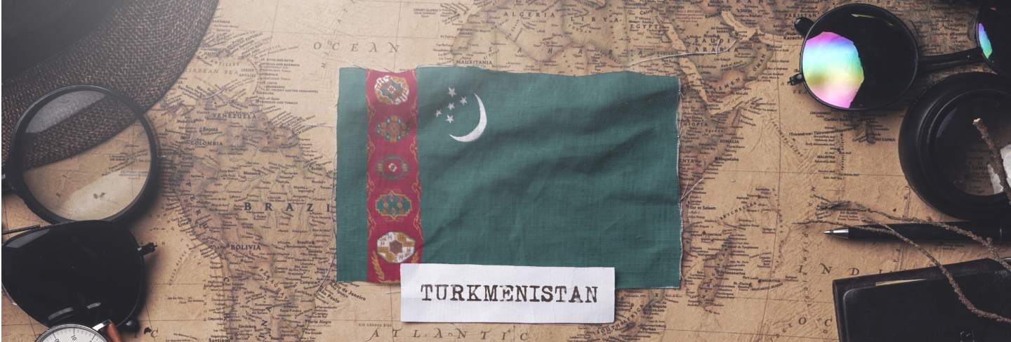 Turkmenistan flag between traveler's accessories on old vintage map. overhead shot