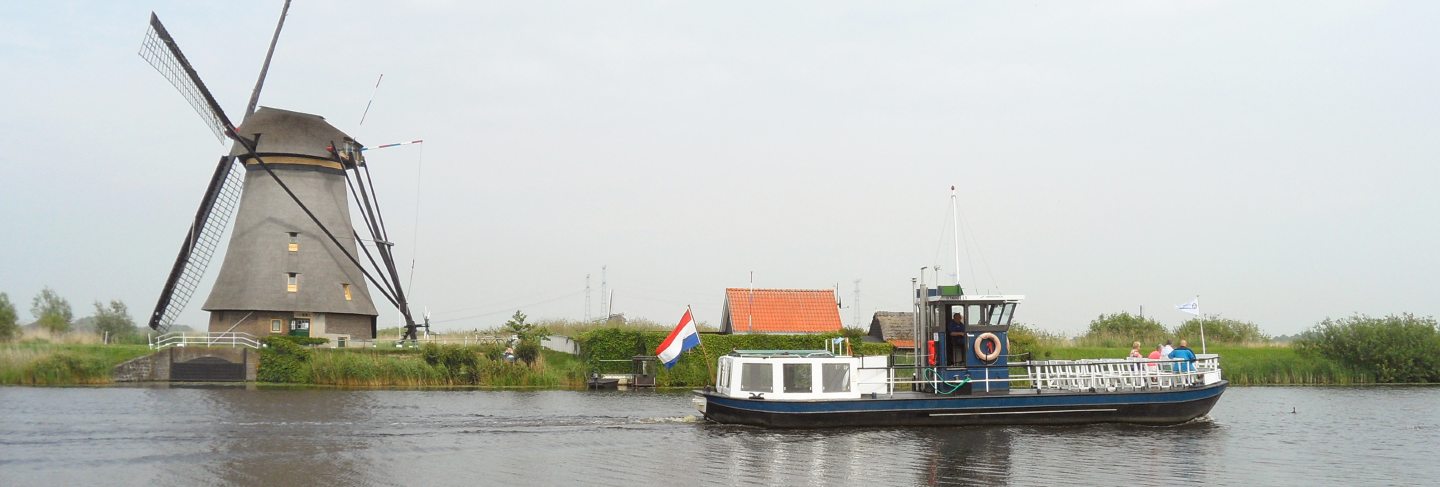 Traditional dutch windmill and boat on the canal at kinderdijk, molenwaard, netherlands