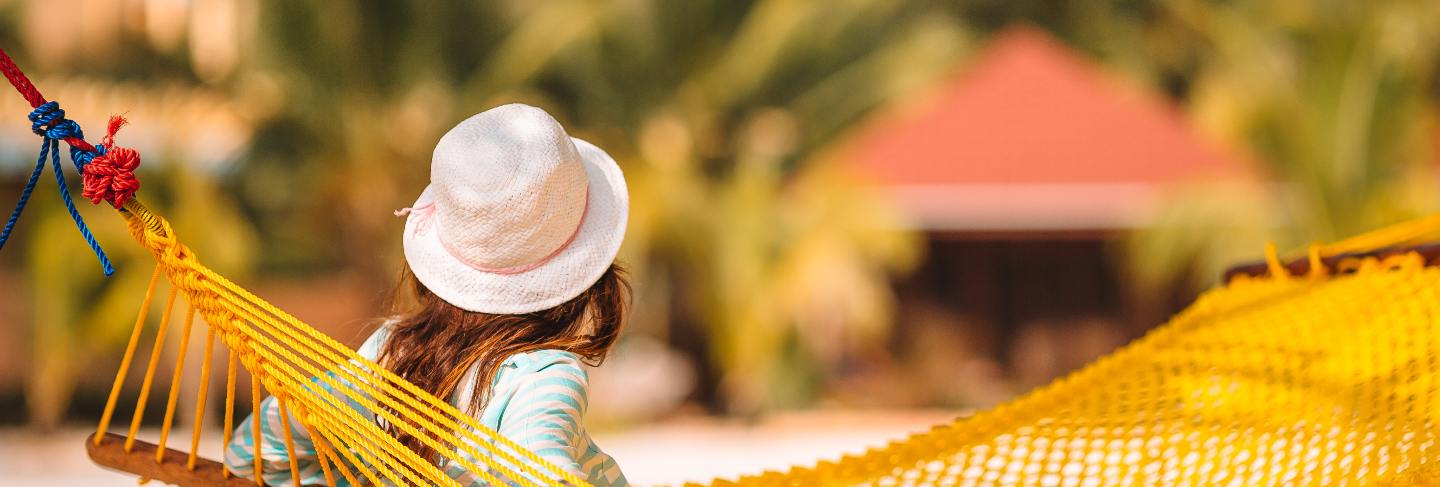 Adorable girl on tropical vacation relaxing in hammock