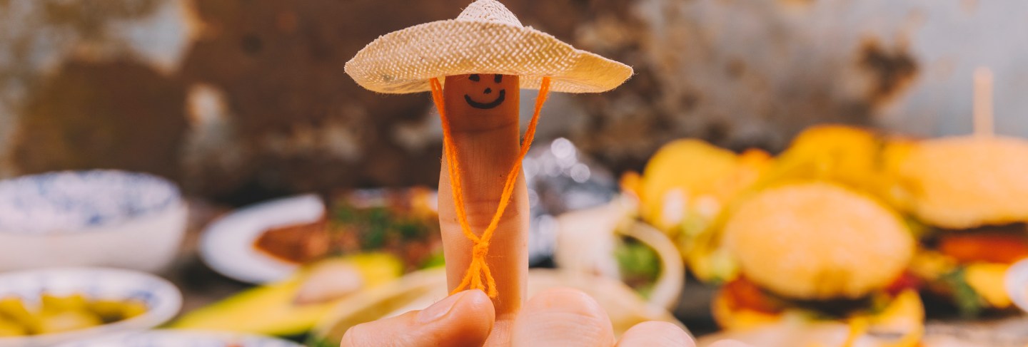 Close-up of finger art with small hat and mexican food at background