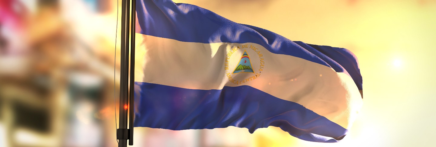 Nicaragua flag against city blurred background at sunrise backlight