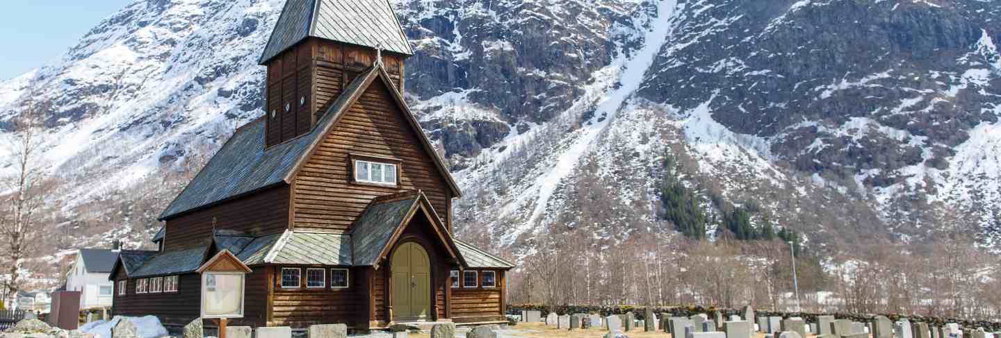 Roldal stave church (roldal stavkyrkje) with snow cap mountain background