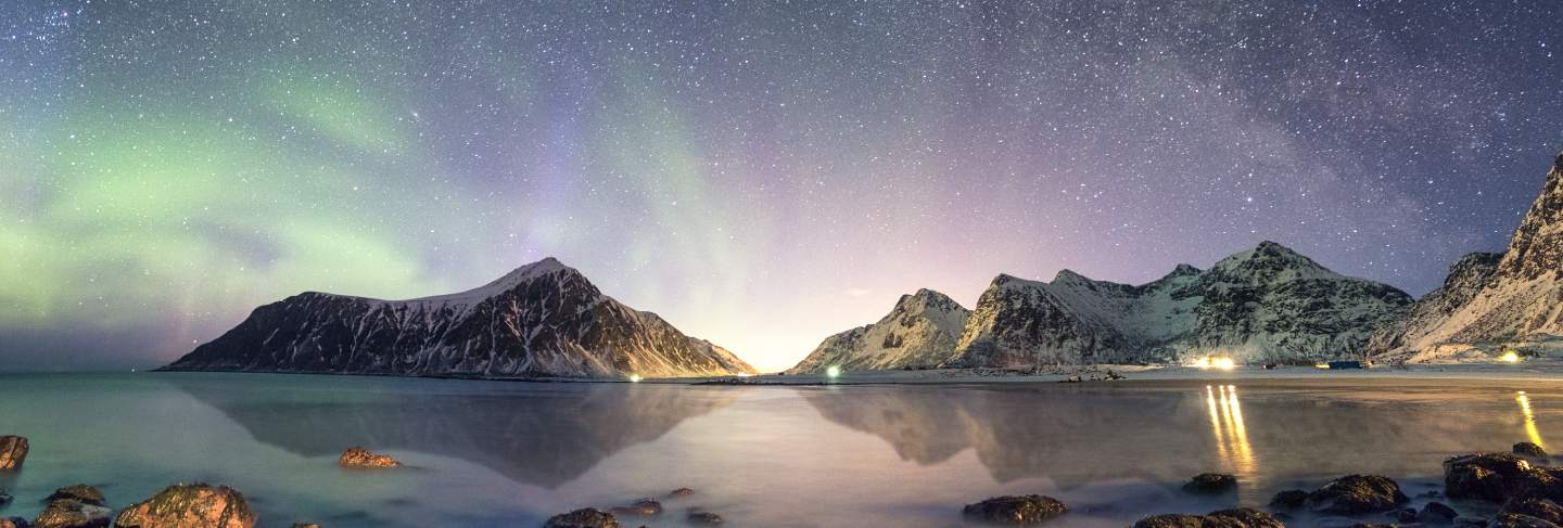 Panorama of aurora borealis with milky way galaxy over snow mountain in coastline