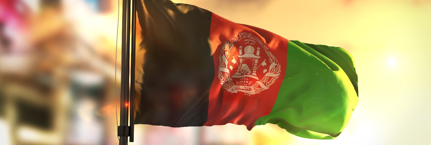 Afghanistan flag against city blurred background at sunrise backlight