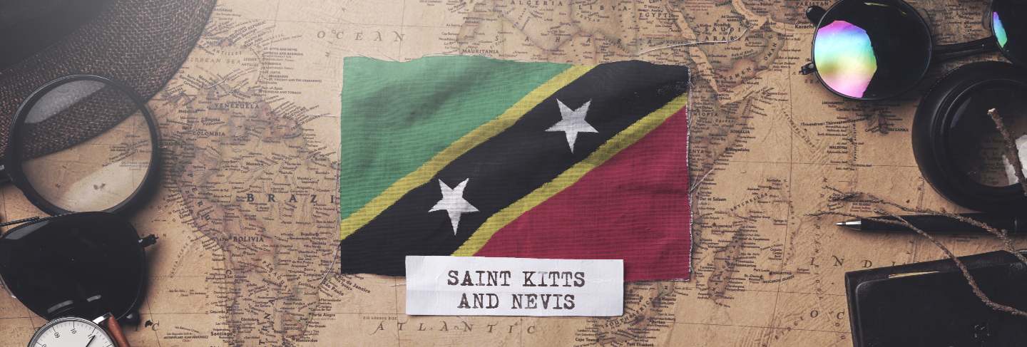 Saint kitts and nevis flag between traveler's accessories on old vintage map.