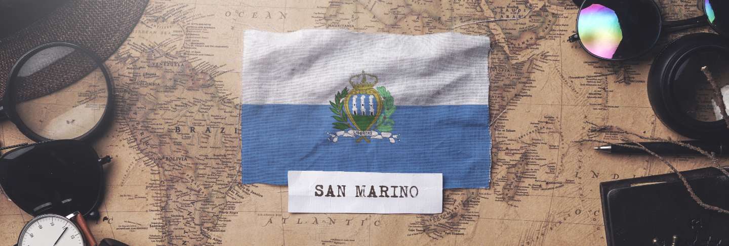 San marino flag between traveler's accessories on old vintage map.