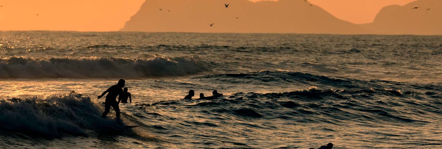 Pacific ocean. silhouettes of the surfers and the mountain at sunset time. lima, peru. south america