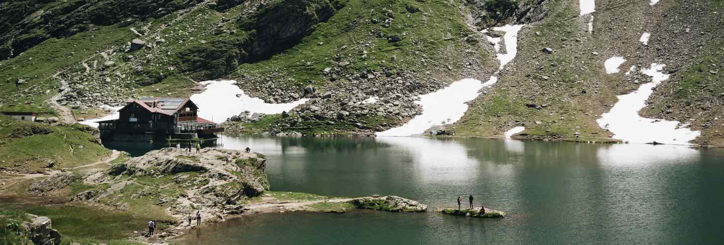 Landscape view of balea lake in romania and fagaras mountains in the summer with snowy peaks