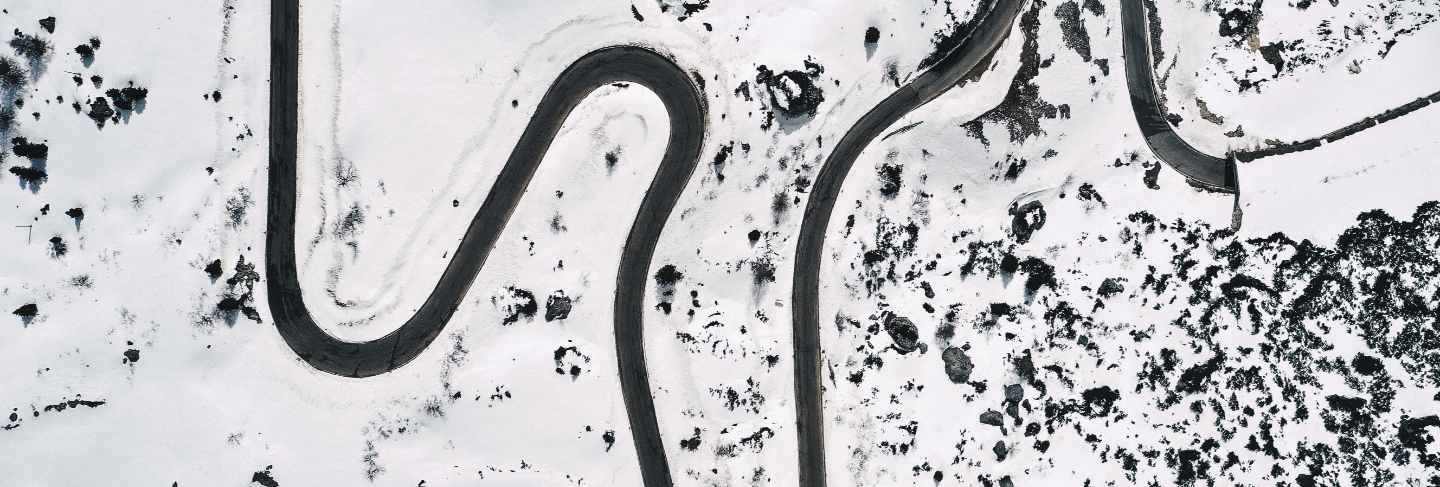 Aerial shot of a beautiful snowy field with a curved road in the middle