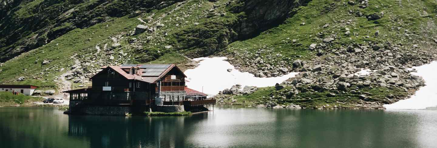 Landscape view of balea lake in romania and fagaras mountains in the summer with snowy peaks