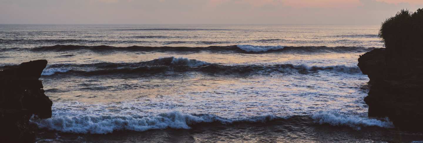 The waves of the ocean are breaking against the rocks. splashing ocean waves at sunset.