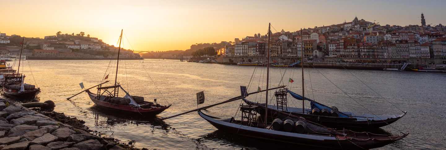 Panoramic of porto cityscape in sunset with river on the front and wine carrier ship in foreground and city of porto in background, portugal