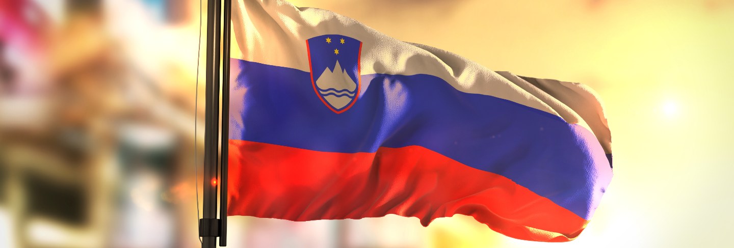 Slovenia flag against city blurred background at sunrise backlight