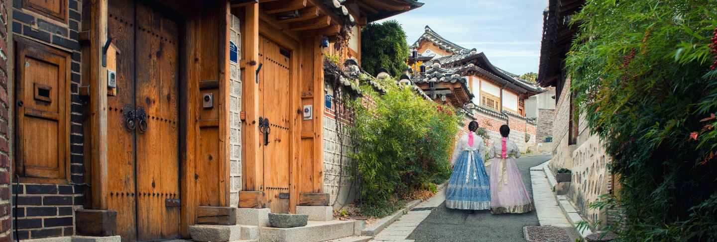 Back of two woman wearing hanbok walking in bukchon hanok village in seoul, south korea.