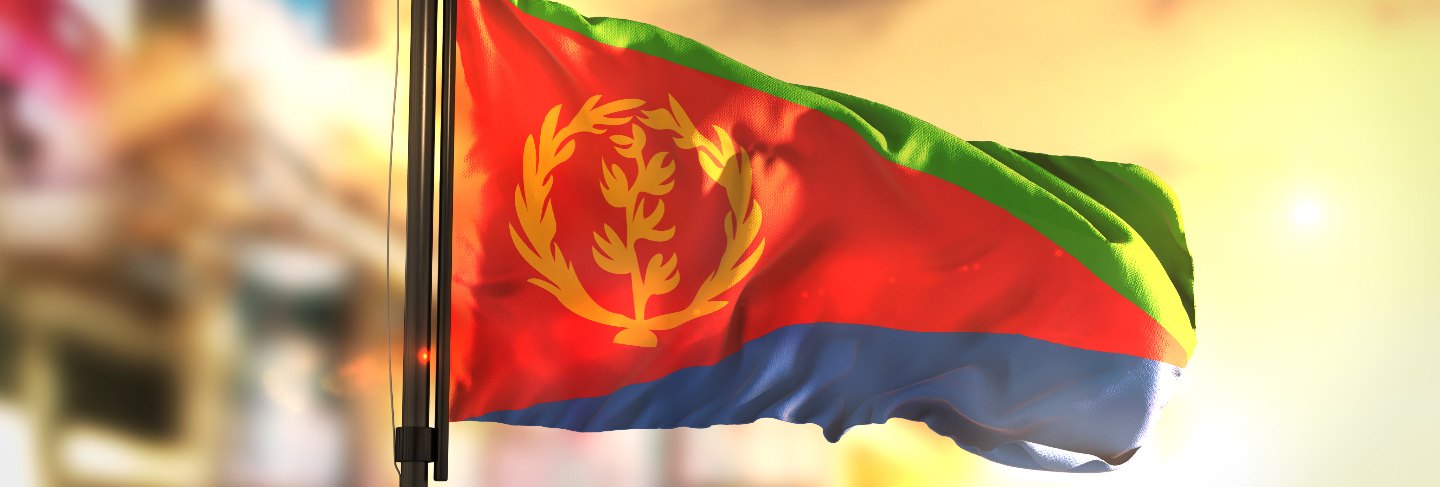 Eritrea flag against city blurred background at sunrise backlight