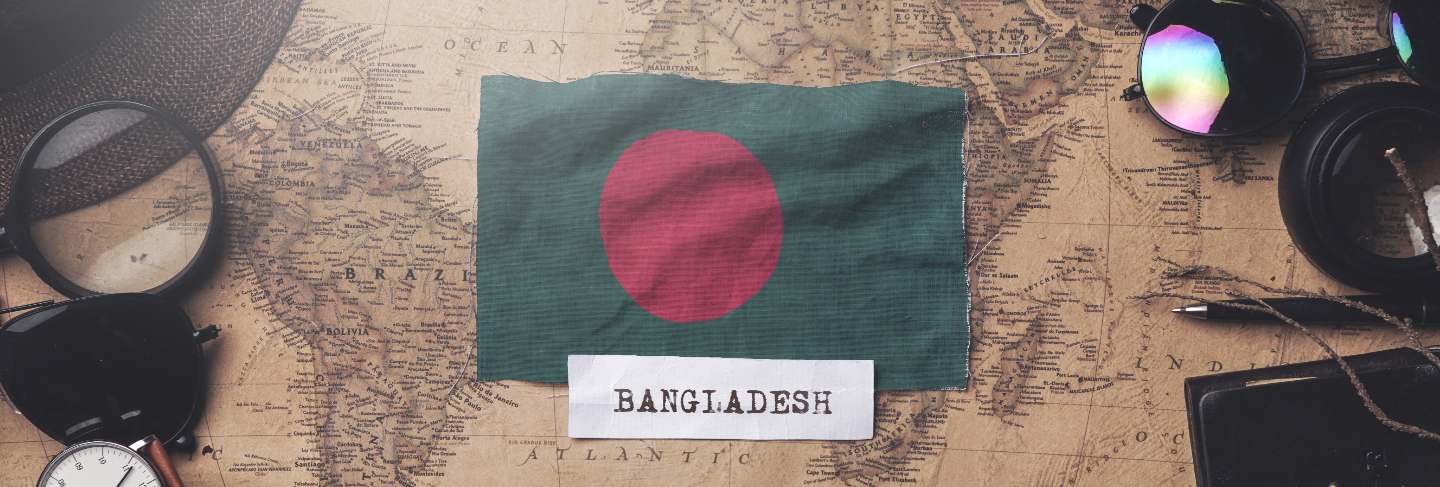 Bangladesh flag between traveler's accessories on old vintage map.