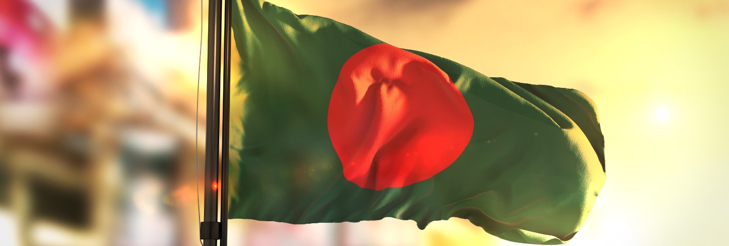 Bangladesh flag against city blurred background at sunrise backlight