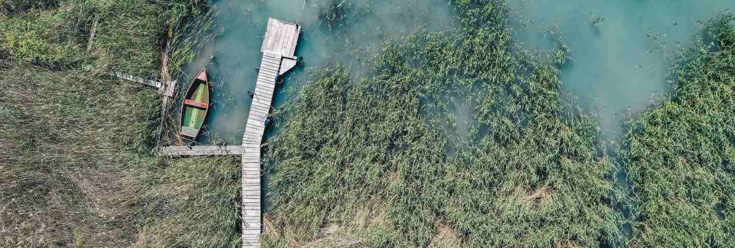 Overhead shot of a wooden dock at the coast with a fishing boat next to it