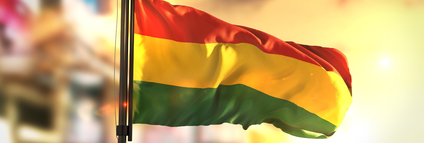 Bolivia flag against city blurred background at sunrise backlight
