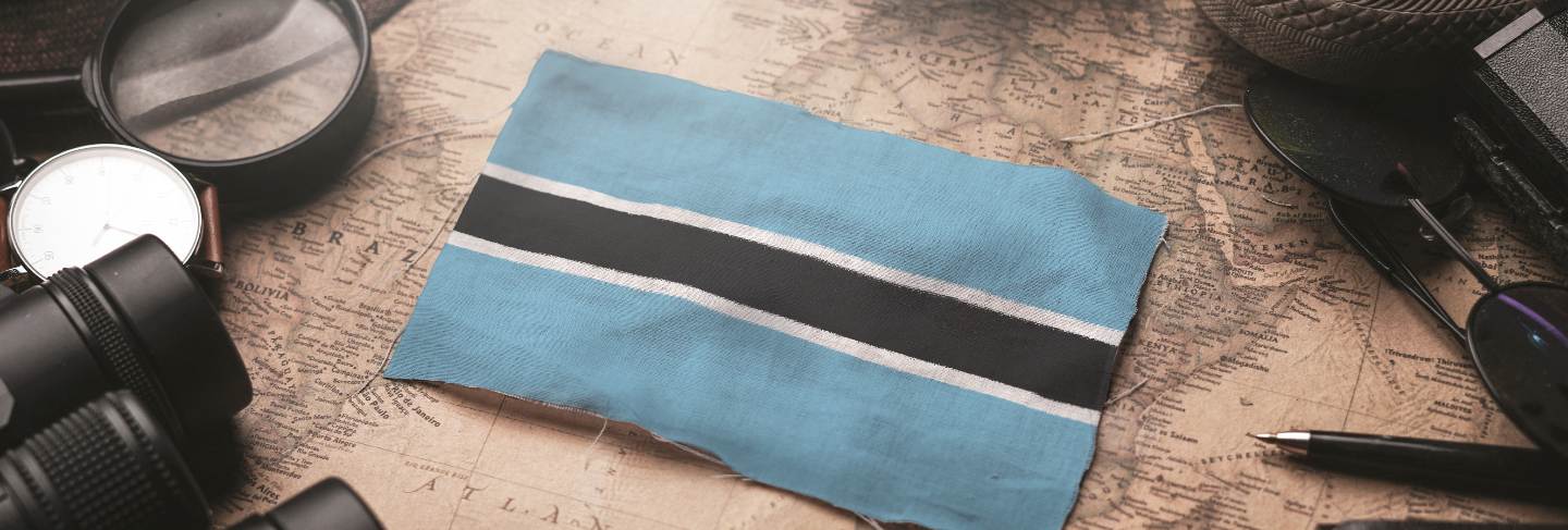 Botswana flag between traveler's accessories on old vintage map.