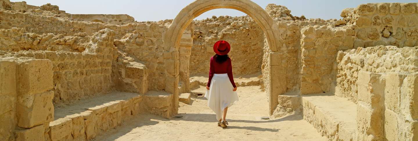 Woman admiring the bahrain fort or qal'at al-bahrain in manama, bahrain 