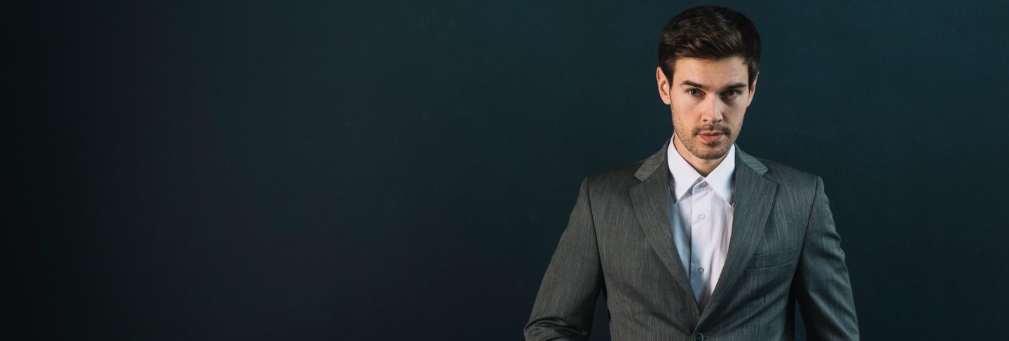 Confident young man with his hand in pocket against black