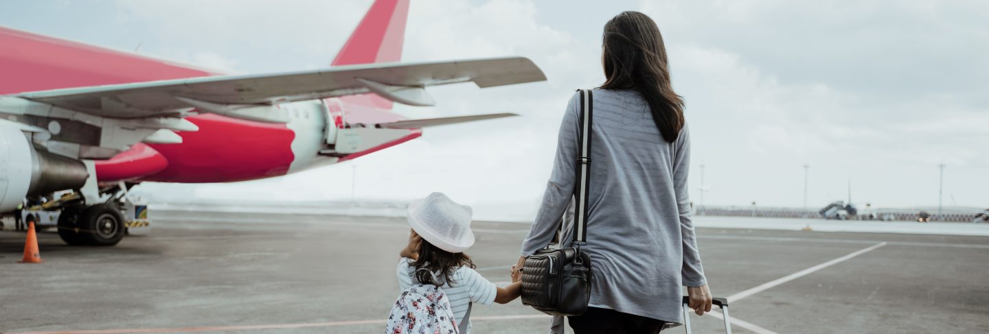 Little girl and mother holding hands walk towards the plane