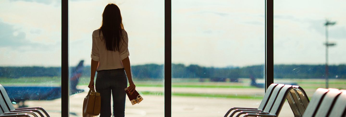 Silhouette of female airline passenger in an airport lounge waiting for flight aircraft 