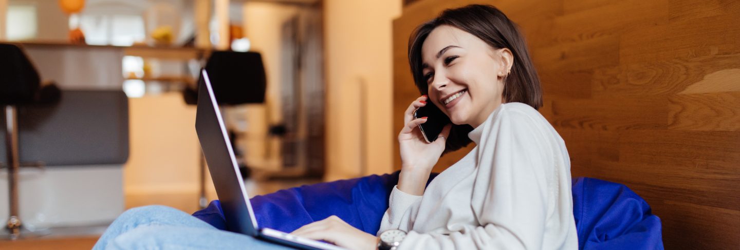 Pretty lady using mobile phone on bag chair in creative office