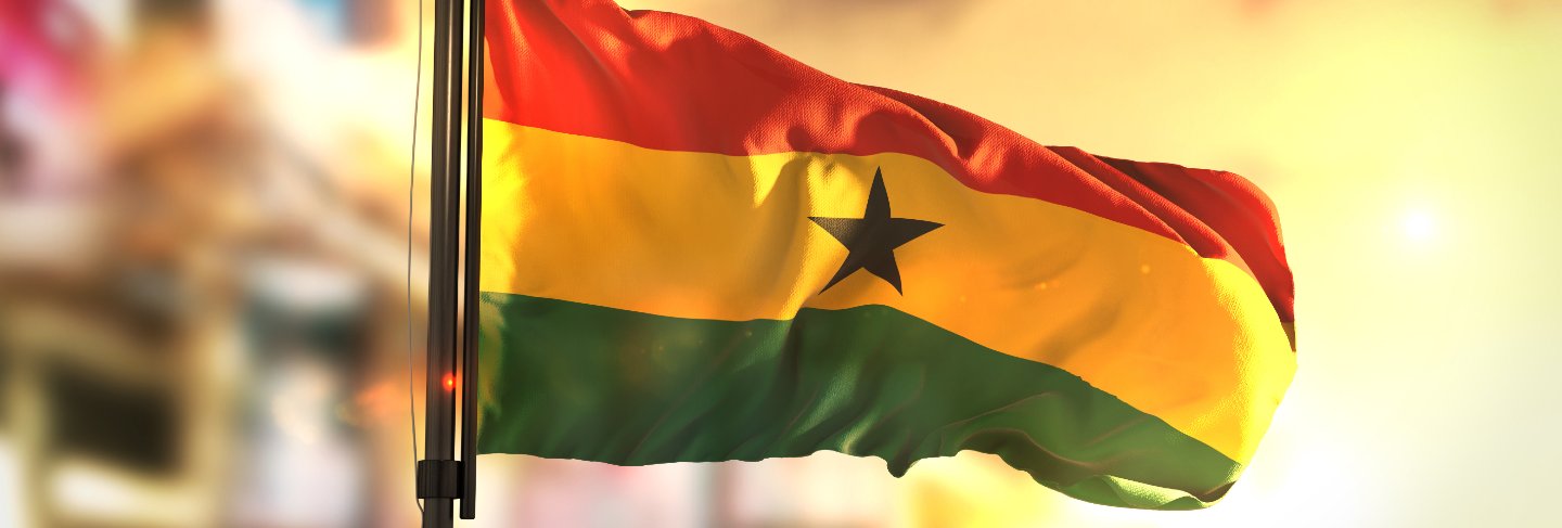 Ghana flag against city blurred background at sunrise backlight