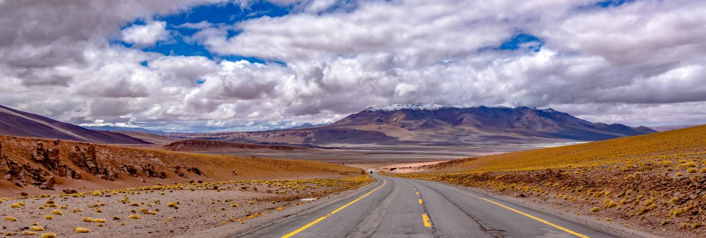 Road in atacama desert savanna, mountains and volcano landscape, chile, south america