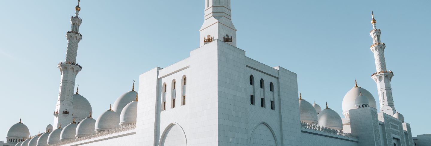 Exterior corner view of huge white mosque with white arch dome