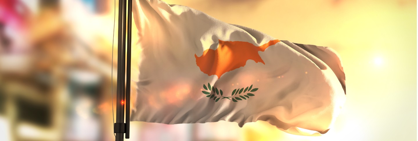 Cyprus flag against city blurred background at sunrise backlight