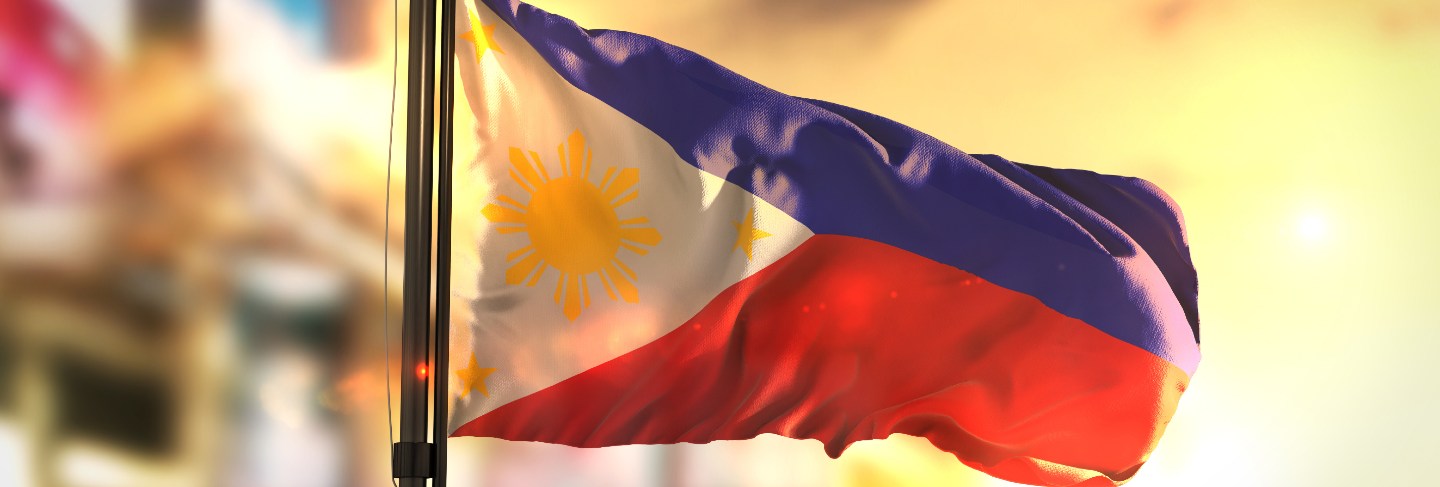 Philippines flag against city blurred background at sunrise backlight
