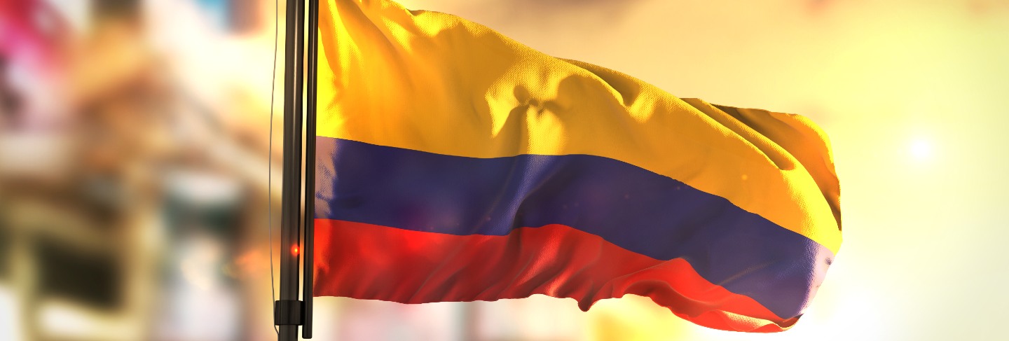 Colombia flag against city blurred background at sunrise backlight