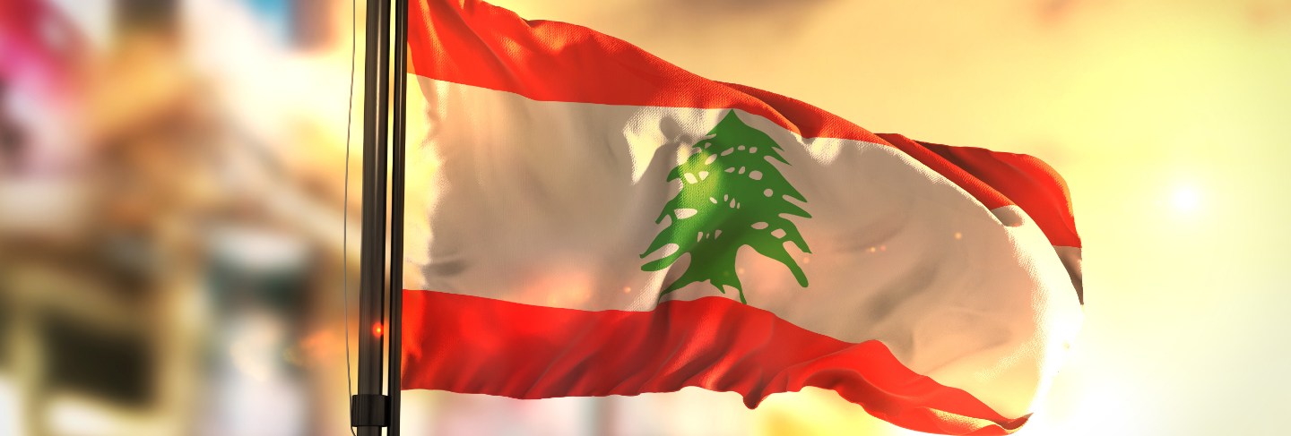 Lebanon flag against city blurred background at sunrise backlight