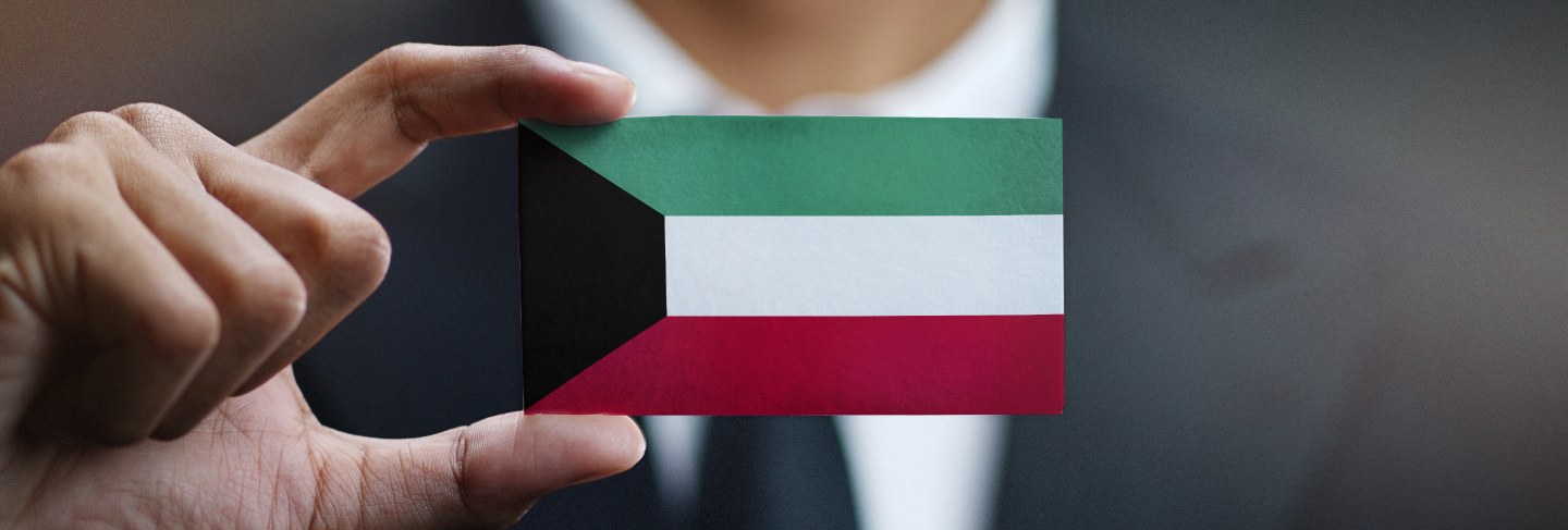 Businessman holding card of kuwait flag