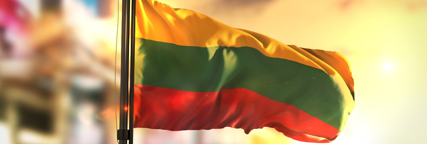 Lithuania flag against city blurred background at sunrise backlight