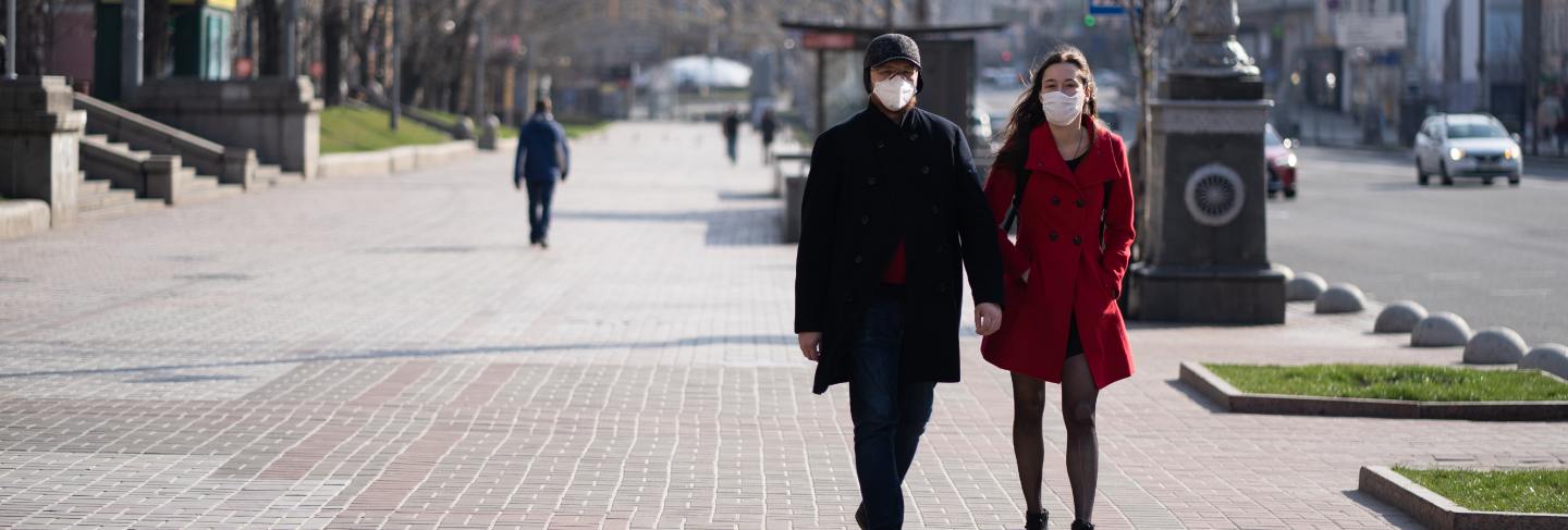 People at facial protective masks at almost empty street
