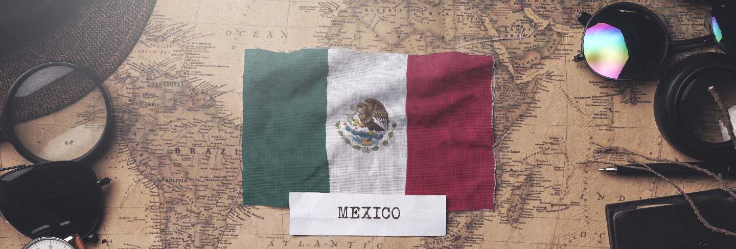 Mexico flag between traveler's accessories on old vintage map. overhead shot