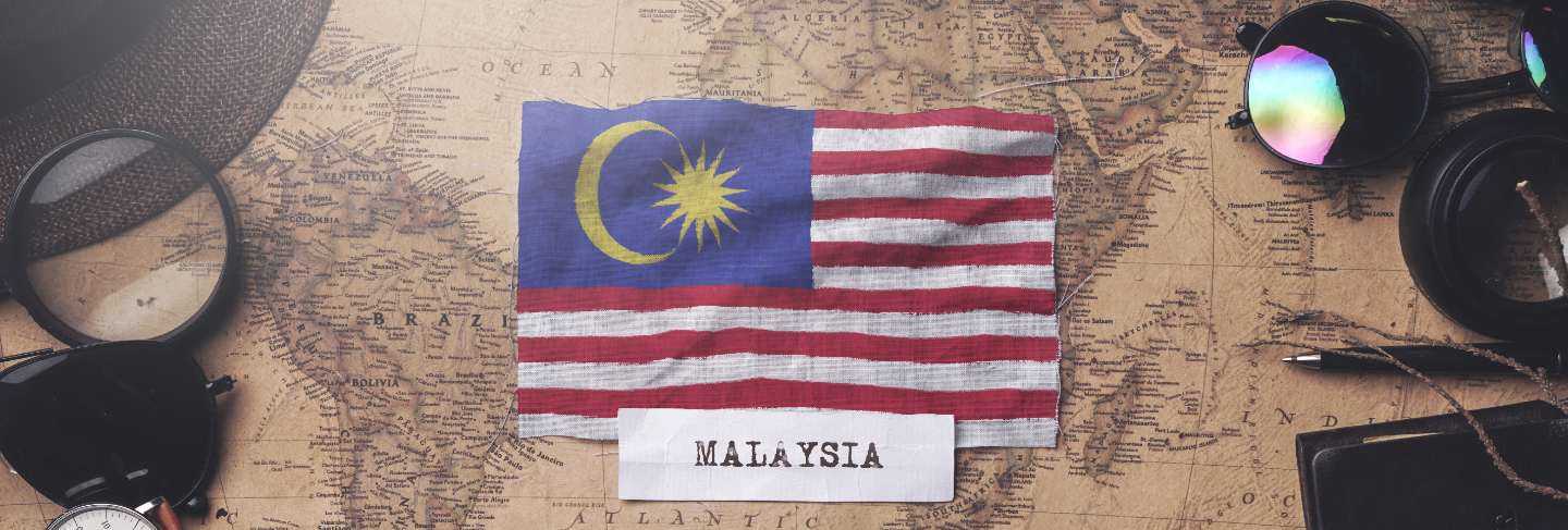 Malaysia flag between traveler's accessories on old vintage map. overhead shot