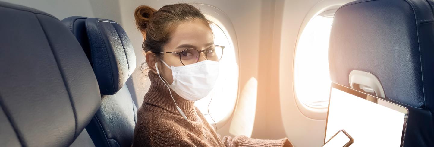 A young woman wearing face mask is traveling on airplane , new normal travel after covid-19 pandemic concept