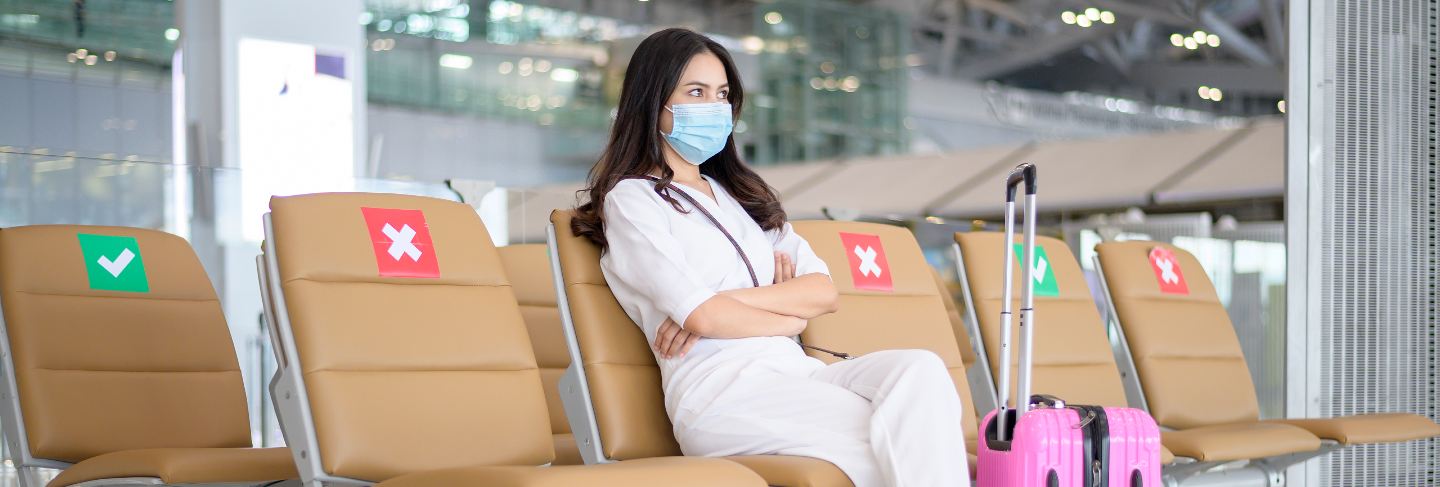 A traveller woman is wearing protective mask in international airport, travel under covid-19 pandemic